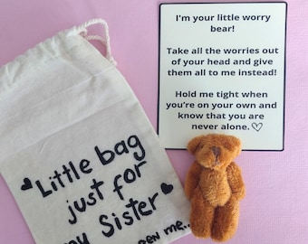 May include: A small, brown teddy bear next to a white bag with the text "Little bag just for my Sister" and a card that reads "I'm your little worry bear!" on a pink background.