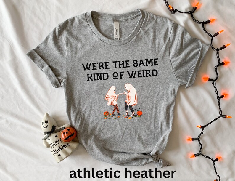 May include: Gray t-shirt with the text "We're the same kind of weird" and a graphic of two ghosts holding hands. The t-shirt is labeled "athletic heather".