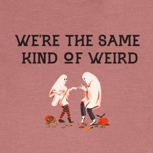 May include: Two white ghosts with black eyes and mouths are dancing with each other. The text "We're the same kind of weird" is above them. There are scattered leaves and pumpkins on the ground.