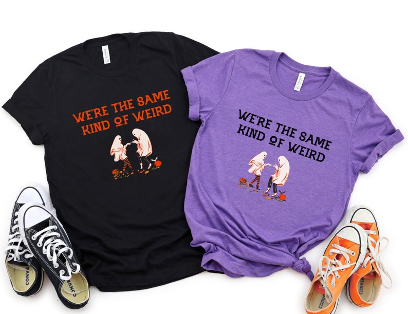 May include: Two black and purple t-shirts with a graphic of two ghosts holding hands and the text "We're the same kind of weird".