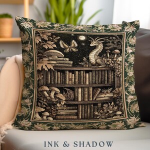 May include: A green woven pillow with a tapestry design featuring a bookshelf filled with books, a dragon, mushrooms, and butterflies. The text "INK & SHADOW Original Fine Art Woven Pillow" is printed below the image.