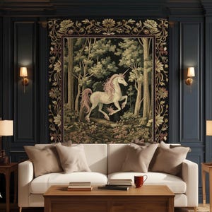 May include: A rectangular wall tapestry featuring a white unicorn with a pink mane and tail standing in a dense forest. The tapestry has a dark floral border and is displayed above a white sofa. The text Ink & Shadow Fine Art Home Decor is visible.