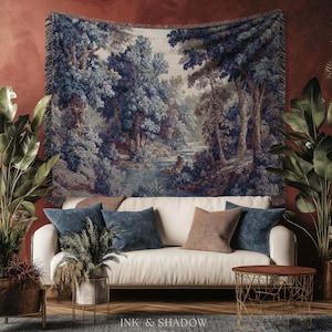 May include: A tapestry depicting a serene forest scene with a river and trees in shades of blue, gray, and brown hangs above a white sofa with blue and brown throw pillows. The room is decorated with plants and a small side table.
