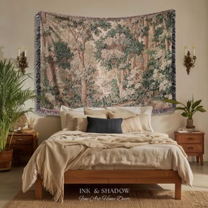 May include: A bedroom scene featuring a tapestry with a forest landscape design hanging above a bed. The bed has a wooden frame, beige bedding, and a dark blue pillow. The room is decorated with plants and sconces.