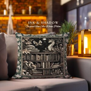 May include: A green and black woven pillow with a bookshelf, a dragon, and a butterfly. The text "INK & SHADOW Original Fine Art Woven Pillow" is printed on the pillow.