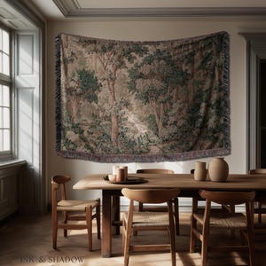 May include: A tapestry depicting a forest scene with trees and foliage in shades of green, brown, and beige. The tapestry is fringed and hangs above a wooden dining table with chairs. The text "INK & SHADOW Fine Art Home Decor" is at the bottom.