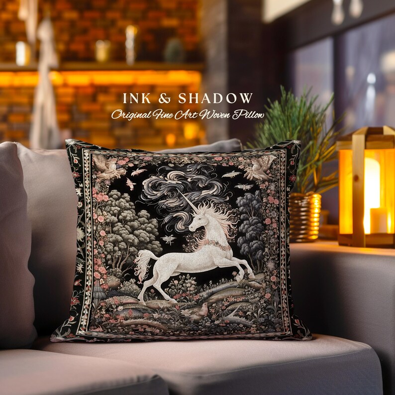 K&ouml;nnte beinhalten: Ein schwarzes und wei&szlig;es gewebtes Kissen mit einem Einhorn, das durch einen Wald mit einer wirbelnden Wolke dahinter rennt. Das Kissen hat einen schwarzen Hintergrund mit rosa und gr&uuml;nen Akzenten. Der Text "INK & SHADOW Original Fine Art Woven Pillow" ist &uuml;ber dem Bild gedruckt.