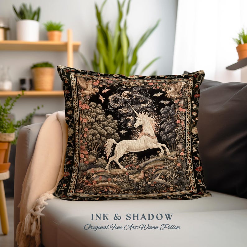 K&ouml;nnte beinhalten: Ein schwarzes und goldenes Wandteppichkissen mit einem wei&szlig;en Einhorn, das durch einen Wald galoppiert. Das Kissen hat einen schwarzen Hintergrund mit goldenen Akzenten und einem floralen Rand. Der Text "INK & SHADOW Original Fine Art Woven Pillow" ist unter dem Kissen gedruckt.