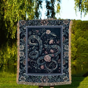 Könnte beinhalten: Eine dunkelblaue Decke mit Blumen- und Schlangenmuster. Die Decke hat einen dekorativen Rand und Fransen. Der Text "INK & SHADOW Original Fine Art Throws" befindet sich am unteren Rand der Decke.