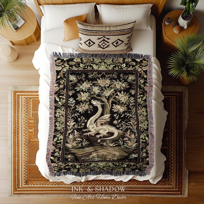 May include: A woven throw blanket featuring a central illustration of a white dragon perched beneath a flowering tree against a black background, framed by a decorative floral border with fringed edges on the top and bottom sides.