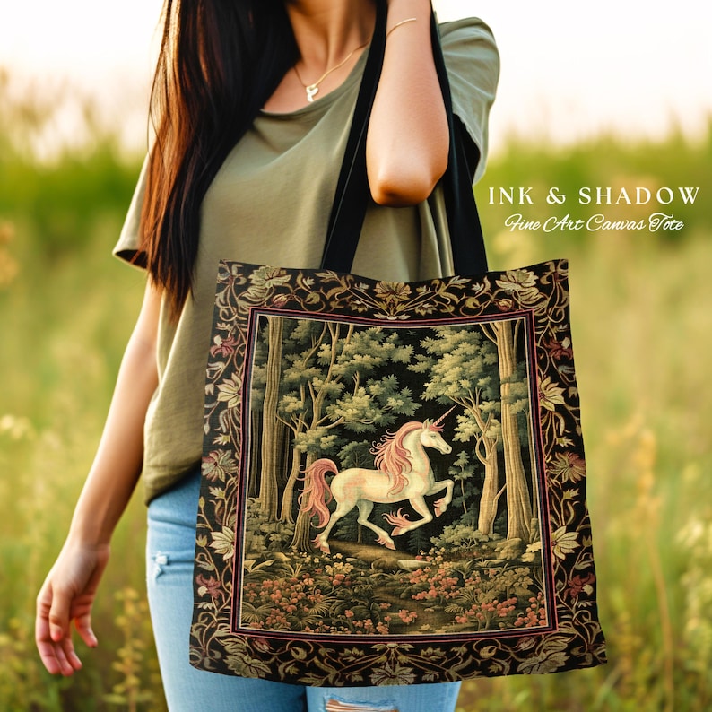 Może przedstawiać: Czarna torba z pł&oacute;tna z białym jednorożcem w scenie leśnej. Torba z pł&oacute;tna ma nadrukowany tekst "INK & SHADOW Fine Art Canvas Tote" na g&oacute;rze.