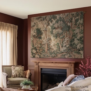 May include: A large tapestry depicting a forest scene with trees and foliage in shades of green, brown, and cream. The tapestry is mounted above a fireplace in a room with burgundy walls. The text "INK & SHADOW Fine Art Home Decor" is visible.