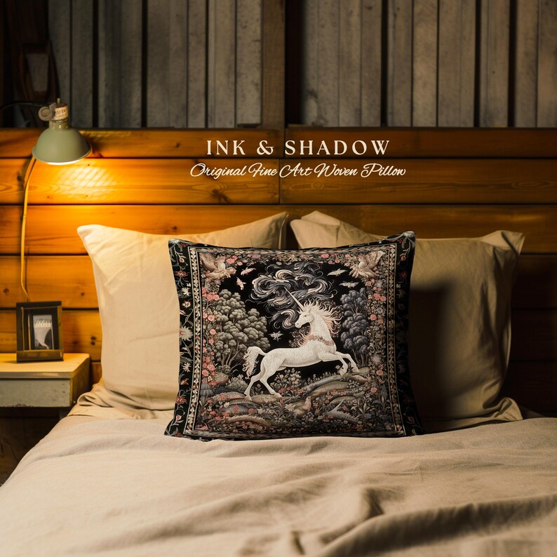 K&ouml;nnte beinhalten: Ein schwarz-wei&szlig; gewebtes Kissen mit einem Einhorn in einer Waldlandschaft. Das Kissen hat einen schwarzen Hintergrund mit einem wei&szlig;en Einhorn und einer farbenfrohen Waldszene. Das Kissen ist mit "INK & SHADOW Original Fine Art Woven Pillow" beschriftet.