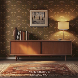 May include: A long wooden sideboard with four cabinet doors stands against a wall with brown floral wallpaper. On top sits a dark vase, a row of books, and a table lamp with a beige shade. A framed black and white forest print hangs above.
