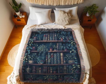 Può includere: Una coperta tessuta con un motivo a scaffale blu scuro riempito di varie piante in vaso e libri. Il testo "INK & SHADOW Original Fine Art Throws" è stampato in bianco nella parte inferiore. La coperta presenta un bordo con frange color crema.