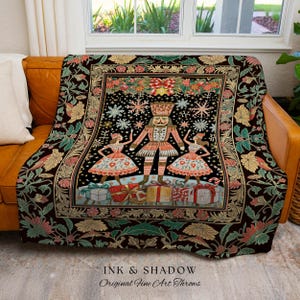 May include: A decorative throw blanket featuring a Nutcracker design with a black background. The blanket has a border with floral and leaf patterns in shades of green, pink, and gold. The text "INK & SHADOW Original Fine Art Throws" is at the bottom.