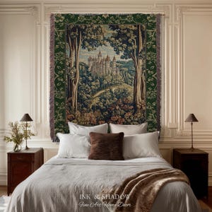 May include: A woven wall tapestry featuring a detailed landscape scene of a castle nestled among trees. The tapestry has a dark green floral border and fringed edges. The central image depicts a stone castle on a hill surrounded by a forest.