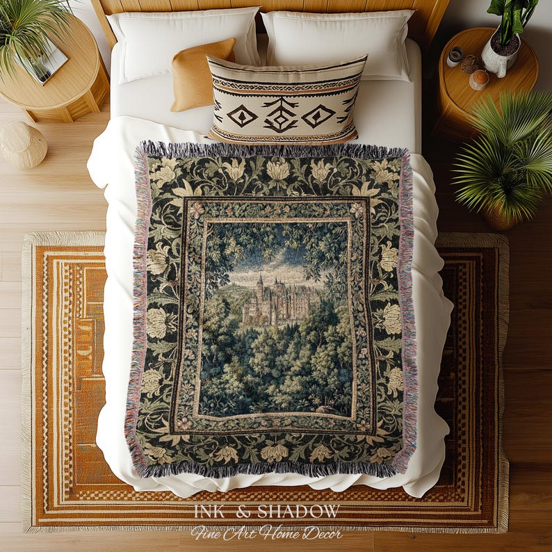 May include: A woven throw blanket featuring a detailed tapestry-style scene of a castle nestled within a dense forest. The design includes a dark floral border with cream and green botanical motifs, finished with a fringed edge on all sides.