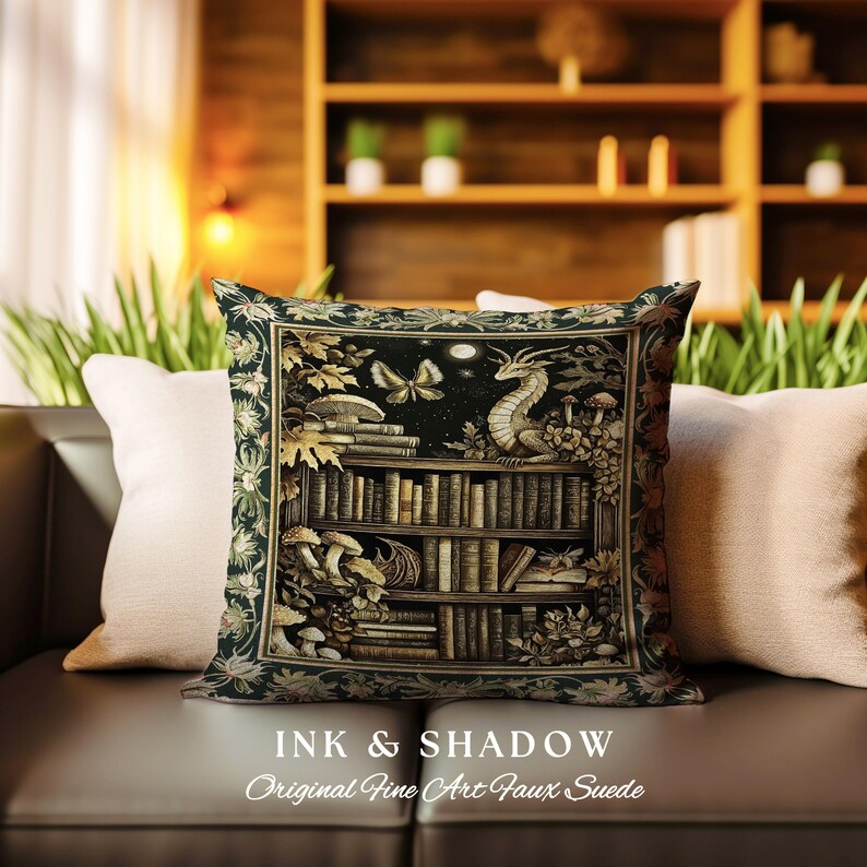 May include: A decorative pillow with a dark green background featuring a bookshelf filled with books, a dragon, and butterflies. The text "Ink & Shadow Original Fine Art Faux Suede" is printed below the image.