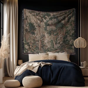 May include: A bedroom scene featuring a tapestry with a forest landscape design above a bed with navy blue bedding. Beige pillows and a throw blanket add warmth. Two woven ottomans sit on a neutral rug. A decorative light fixture hangs from the ceiling.