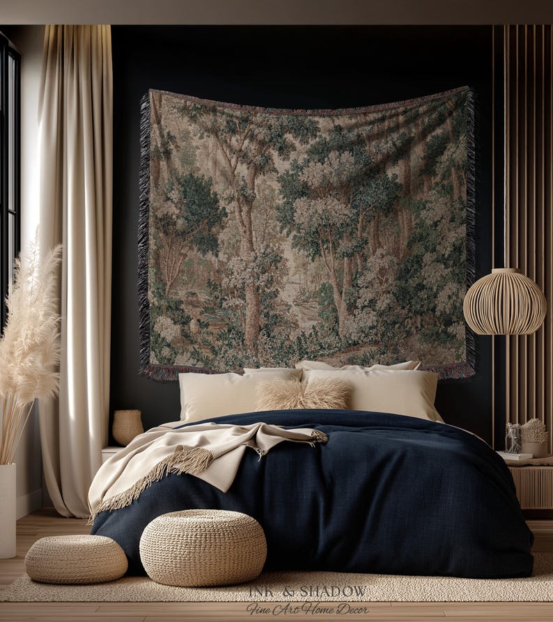 May include: A bedroom scene featuring a tapestry with a forest landscape design above a bed with navy blue bedding. Beige pillows and a throw blanket add warmth. Two woven ottomans sit on a neutral rug. A decorative light fixture hangs from the ceiling.