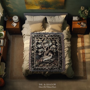 May include: A rectangular woven throw blanket featuring a detailed illustration of a white dragon resting beneath a large tree. The design is set against a black background with a decorative floral border and fringed edges on the top and bottom.