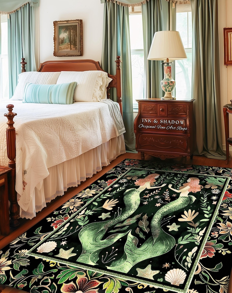 May include: A dark green area rug features two mermaids with flowing tails, surrounded by floral and shell designs. The rug has a black background with gold accents. The text 'INK & SHADOW Original Fine Art Rugs' is visible on a wooden nightstand in the background. The rug is displayed in a bedroom setting with a wooden bed and light teal curtains.