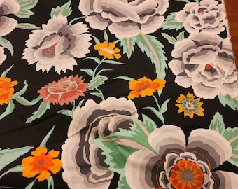 May include: Black fabric with a large floral pattern. The design features oversized flowers in shades of gray, white, orange, and red, set against a black background. Green leaves and smaller orange flowers add contrast.