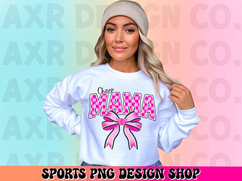 May include: White sweatshirt with the text "Cheer Mama" in pink and black checkered letters with a pink bow.