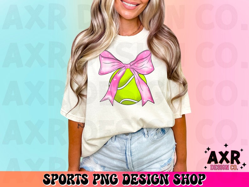 May include: A white t-shirt with a pink bow and a green tennis ball design. The design features a pink bow with glitter accents and a green tennis ball with white stitching.
