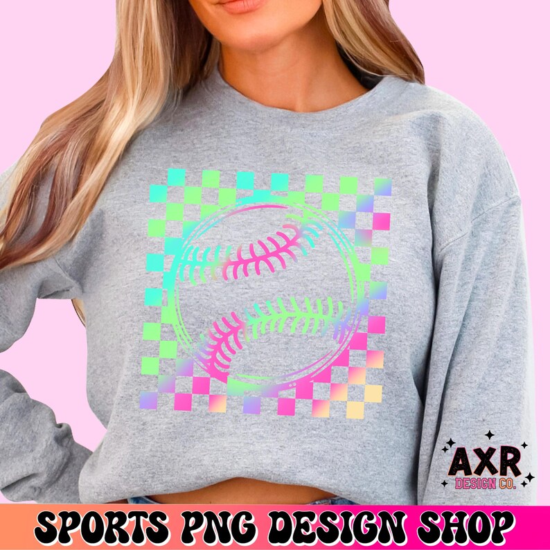 May include: A gray sweatshirt featuring a baseball design with a colorful checkered pattern. The baseball graphic is outlined in a gradient of pink, blue, and green. The text "SPORTS PNG DESIGN SHOP" is at the bottom.