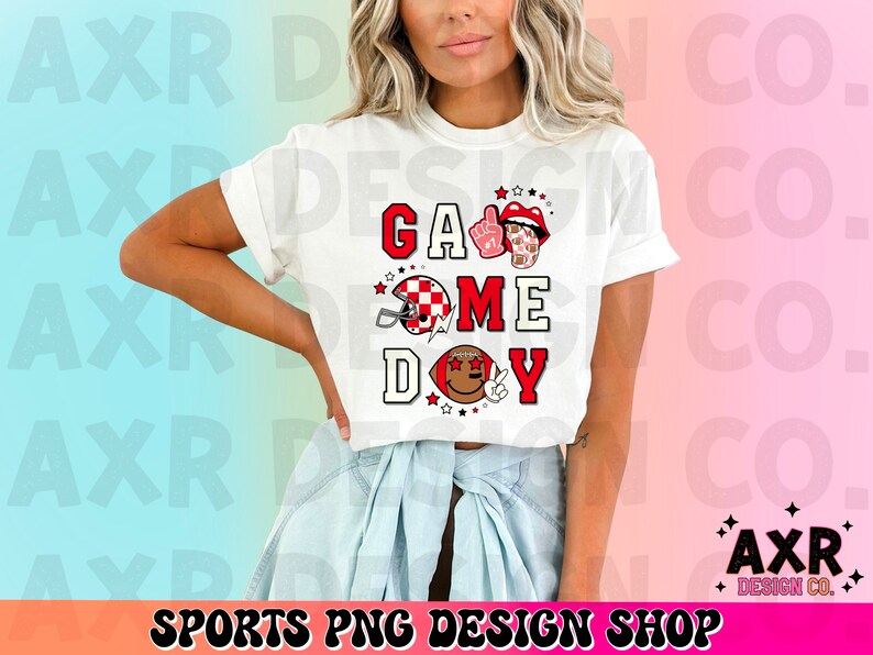 May include: White t-shirt with a red, white, and black graphic that says "Game Day" with a football helmet, a red mouth, and a winking brown eye.