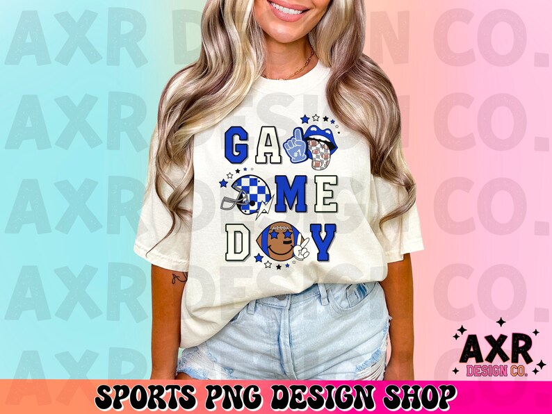 May include: White t-shirt with a blue, white, and black graphic design that says "Game Day". The graphic includes a football helmet, a football, and a hand giving a thumbs up.