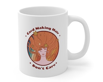May include: White ceramic mug with a colorful illustration of a woman with long flowing hair and stars. The text "Card Making Hair Don't Care" is printed on the mug.