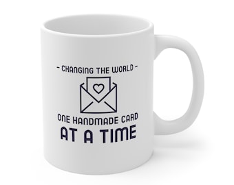 May include: White ceramic mug with a blue graphic of an envelope with a heart inside. The text reads "Changing the world - one handmade card at a time."