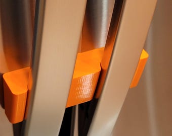 May include: Close-up of three orange plastic spacers on a stainless steel surface.