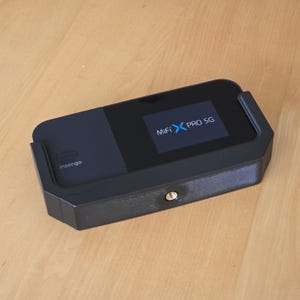 May include: A black MiFi X PRO 5G mobile hotspot with a blue logo and the text "inseego" on the side. The device is mounted in a black plastic case with a tripod mount.