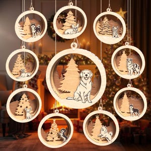 May include: A collection of ten circular wooden ornaments featuring layered cutouts of various dog breeds, including a golden retriever, husky, and french bulldog, each set against a backdrop of a pine tree and snowy landscape.