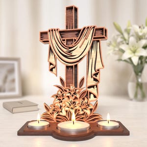 Può includere: Una scultura a croce in legno a strati con un design in tessuto drappeggiato e una base di gigli intagliati. La struttura è montata su un supporto in legno scuro con tre fori circolari che ospitano candeline bianche accese.