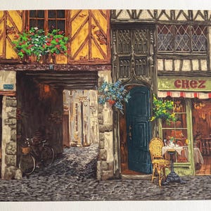 May include: A detailed painting of a European street scene. Buildings with timber framing, stone walls, and flower boxes. A bicycle is parked in an arched passageway. A cafe with a red and white striped awning and the text "Chez Luc" is on the right.