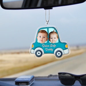 May include: A blue car shaped rearview mirror charm with two children's faces in the windows. The car has the text "Drive Safe Daddy" on the bottom.