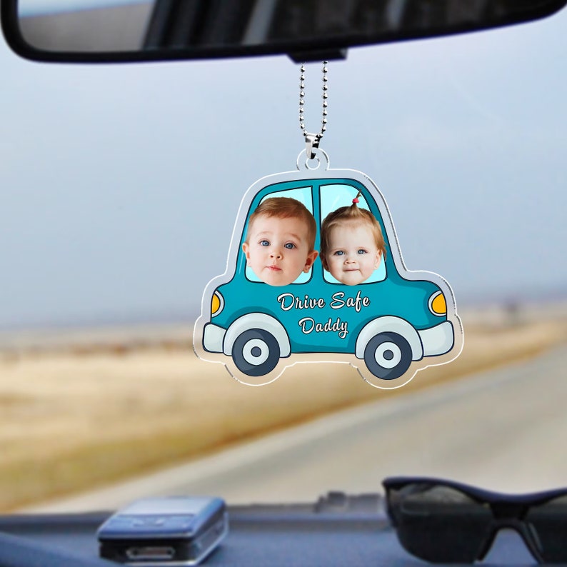 May include: A blue car shaped rearview mirror charm with two children's faces in the windows. The car has the text "Drive Safe Daddy" on the bottom.
