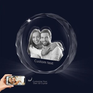 May include: A 3D crystal sphere with a photo of a couple inside. The sphere is clear and has a faceted design. The photo shows a man and a woman smiling and looking at each other. The text "Custom text" is printed on the sphere.