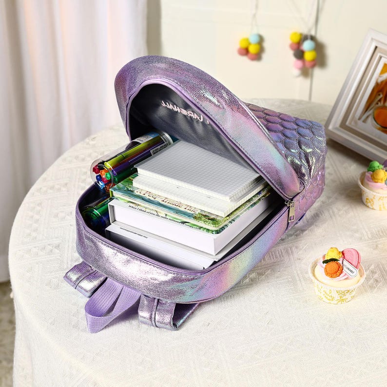 Pu&ograve; includere: Zaino viola iridescente con motivo a scaglie di sirena, aperto per rivelare libri, quaderni e penne colorate. Lo zaino ha spallacci regolabili e chiusura a zip. L'interno &egrave; nero con testo bianco. Una borsa da scuola divertente ed elegante.
