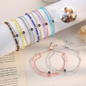 May include: A set of colorful beaded bracelets with a small black charm in the center. Each bracelet has a different color and pattern of beads. The bracelets are adjustable and can be worn on the wrist or ankle.