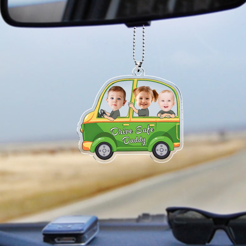 May include: Green car shaped rearview mirror charm with three children's faces inside. The car has yellow wheels and the text "Drive Safe Daddy" on the side.