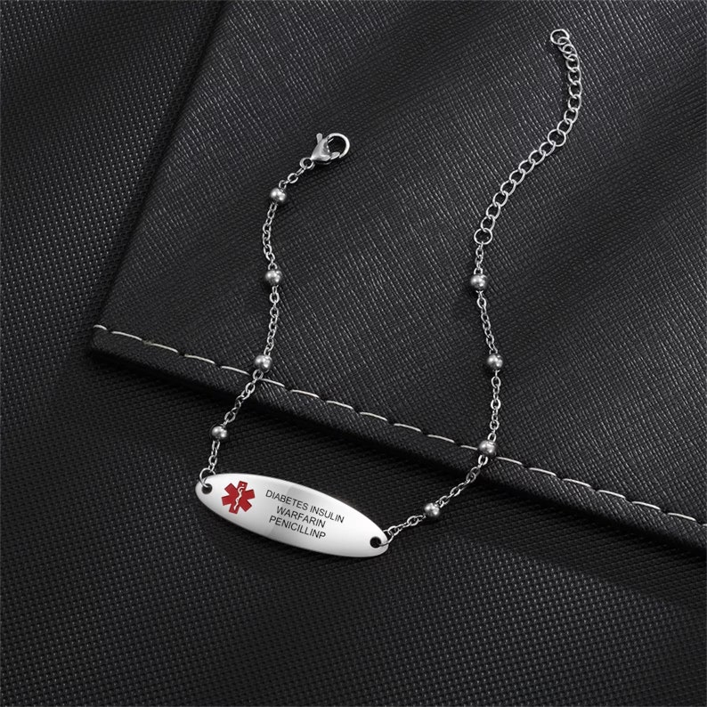 May include: A silver medical alert bracelet with a red medical symbol and the text "DIABETES INSULIN WARFARIN PENICILLIN".