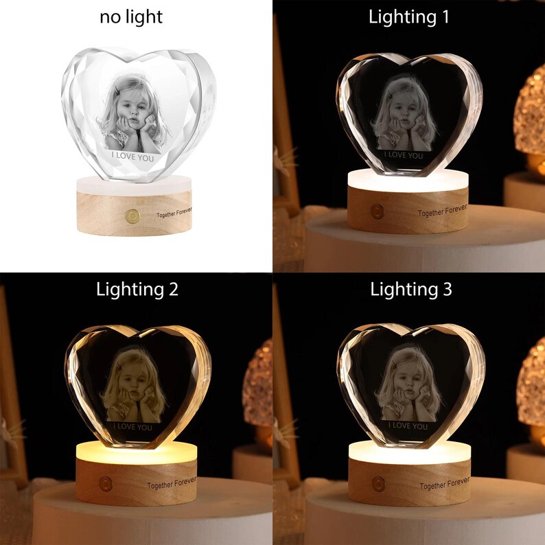 May include: A heart-shaped crystal with a photo inside, on a wooden base with a light. The crystal is illuminated with different lighting options, showing the photo in various ways. The base has the text "Together Forever" engraved on it.