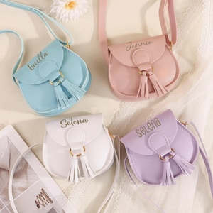 May include: Four small, pastel-colored crossbody bags with matching straps. Each bag has a flap closure, a tassel, and a name printed on the front: Lucilla, Jennie, Selena, and Selena. The bags are in shades of blue, pink, white, and purple.