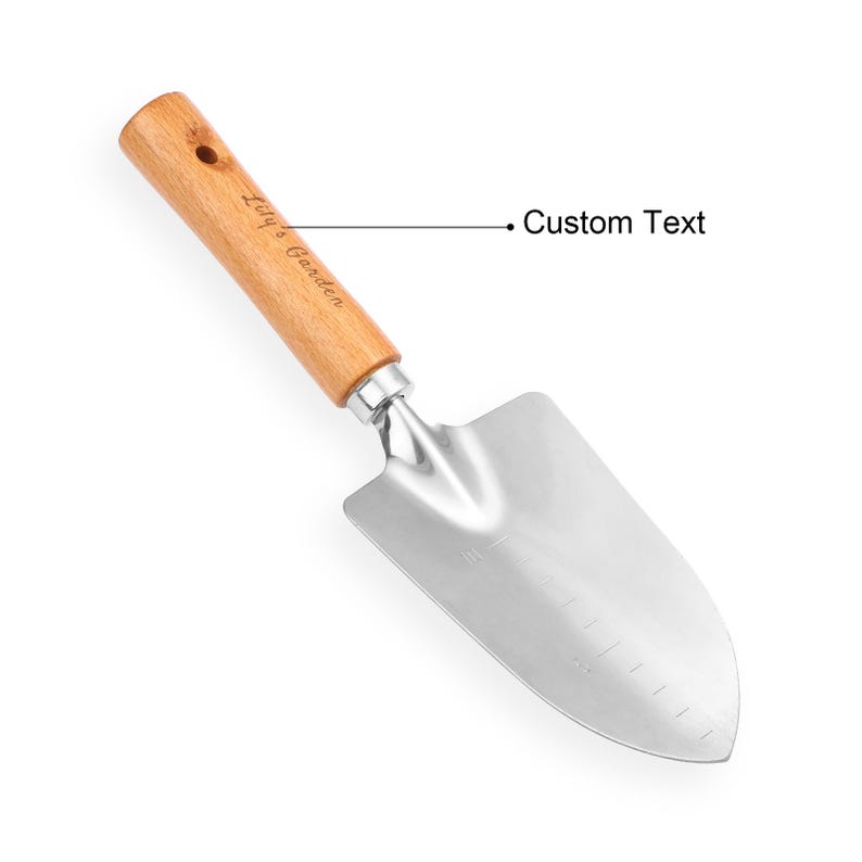 May include: A gardening trowel with a wooden handle and a stainless steel blade. The handle is light brown and has the text "Lily's Garden" printed on it. The blade is silver and has measurement markings.